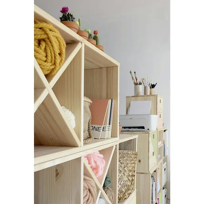 Astigarraga Dinamic Estantería para botellas - L x An x Al: 33 x 32,5 x 32,5 cm, Madera - Esta foto muestra una estantería de madera clara decorada con coloridos ovillos de lana, pequeños cactus y una colección de libros.