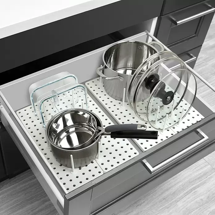 Umbra Schubladeneinsatz-Set Peggy - 45 cm, 15 cm, 1 cm, Weiß - Weißes Schubladen-Ordnungssystem mit verstellbaren Stiften, das Edelstahltöpfe, Pfannen, Glasdeckel und Behälter ordentlich in einer Küchenschublade organisiert.