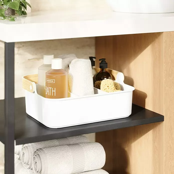 Umbra Aufbewahrungsbox Bellwood - L x B x H: 35 x 13 x 26 cm, Kunststoff, Weiß/Natur - Weißer Bad-Organizer aus Kunststoff mit Holzgriff, gefüllt mit Badeölen, Handtüchern und Schwämmen, auf einem dunklen Regal.