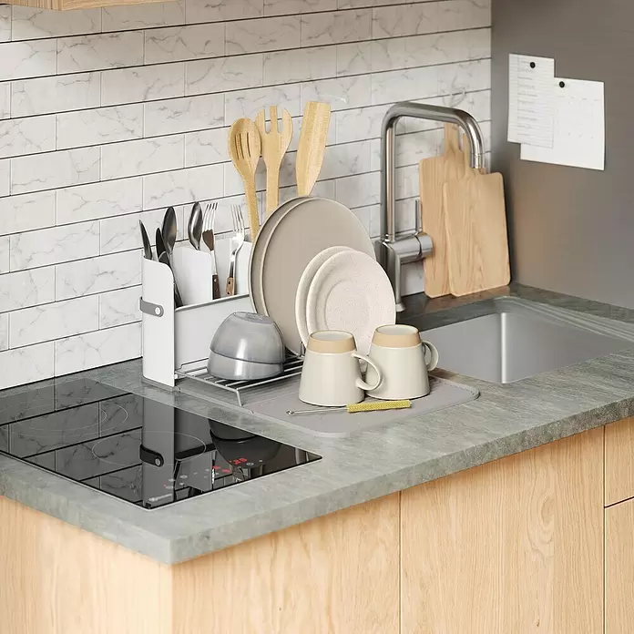 Umbra Abtropfgestell Sling - L x B x H: 33 x 38 x 17 cm, Kunststoff, Grau-Weiß - Graues Silikon-Abtropfgitter mit weißem Utensilienhalter, beigem Geschirr, Holzküchenhelfern und Besteck, an einer Spüle.