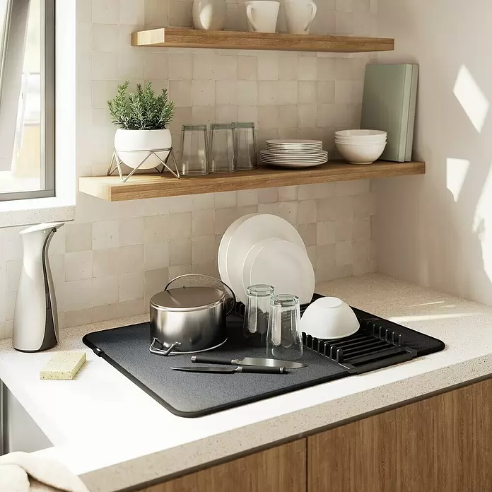 Umbra Abtropfmatte Udry - L x B x H: 61 x 46 x 4 mm, Kunststoff, Schwarz - Schwarze Geschirrabtropfmatte mit Gestell auf einer Küchentheke, mit Geschirr, Gläsern und einem Topf.