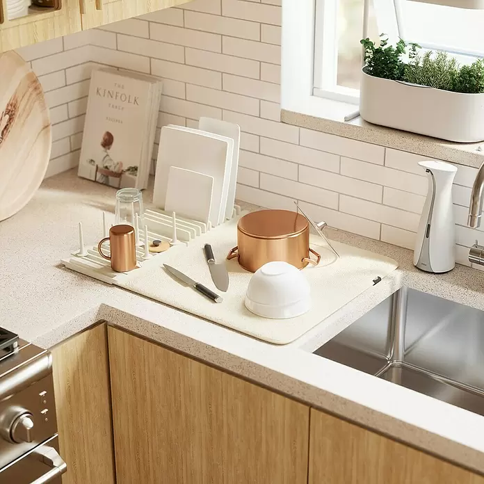 Umbra Abtropfmatte Udry Peg - L x B x H: 47 x 17 x 9 cm, Kunststoff, Beige - Eine beige Abtropfmatte mit weißem Gestell hält Kupfer- und weißes Geschirr, Topf, Messer in einer Küche.