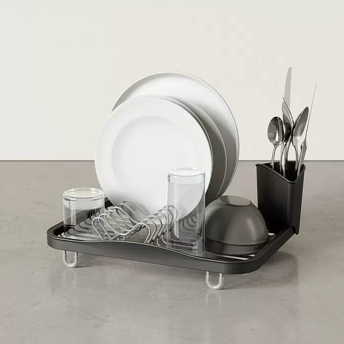 Umbra Abtropfgestell Sinkin - L x B x H: 36 x 28 x 14 cm, Edelstahl, Schwarz-Nickel - Dunkelgraues Abtropfgestell mit silbernem Drahteinsatz, weißen Tellern, Gläsern, einer dunklen Schale und Besteck.