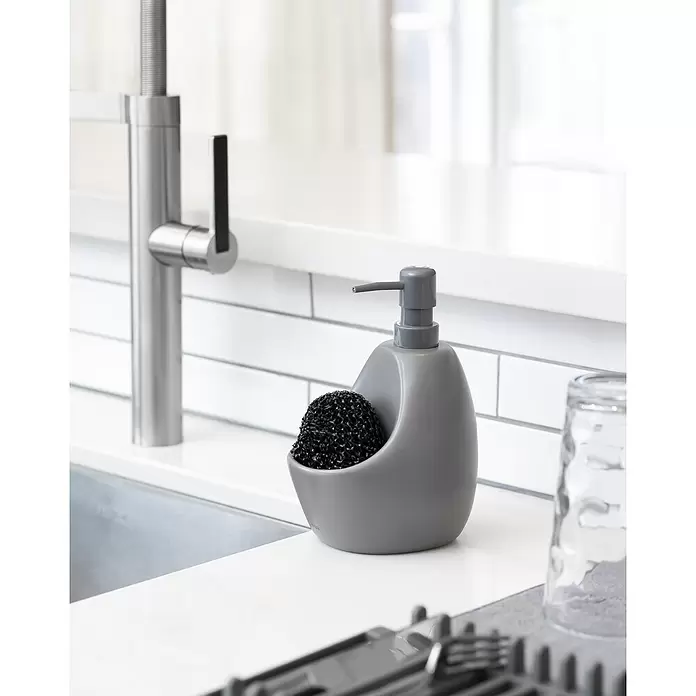 Umbra Seifenspender Joey - Kunststoff, Anthrazit, 590 ml - Grauer Seifenspender mit schwarzem Topfreiniger im integrierten Halter, auf einer Küchenzeile an der Spüle.