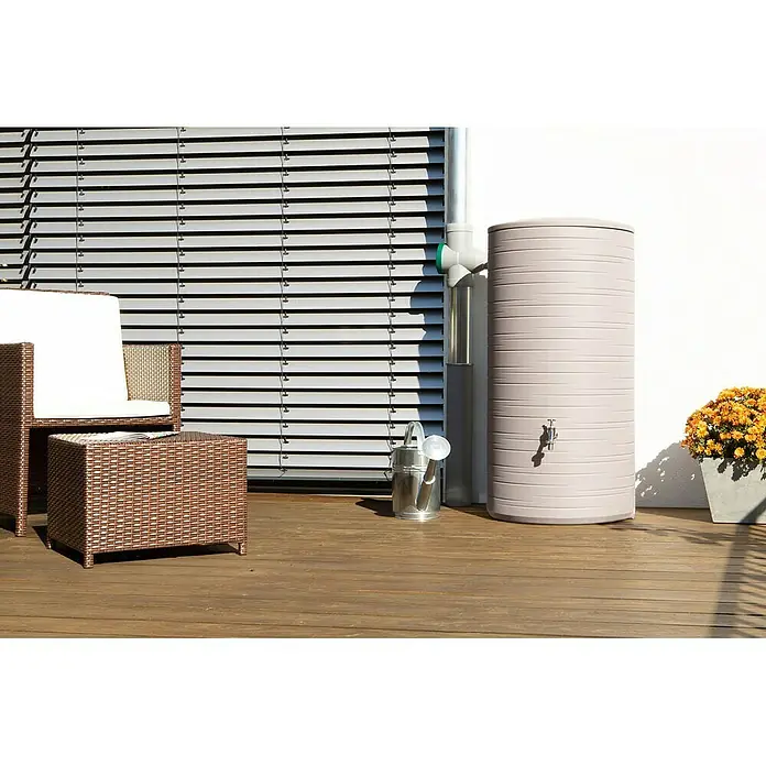 Arves Regenspeicher Novara - 280 l, Taupe - Ein stilvoller Regenwassertank auf einer Holzterrasse, neben einem Rohr und einer kleinen Gießkanne.