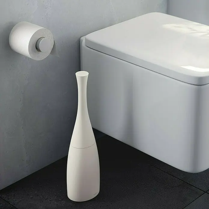 Cosmic Saku Escobillero de suelo - Altura: 38,5 cm, Plástico, Piedra - Un escobillero blanco con soporte está al lado de un inodoro moderno y un rollo de papel higiénico en la pared.