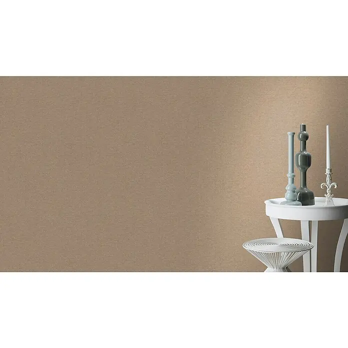 SCHÖNER WOHNEN-Kollektion Cosyliving Vliestapete LINEN - Hellbraun, Uni, 10,05 x 0,53 m - Ein hellbrauner Hintergrund mit einem weißen Beistelltisch mit Vasen und einer Kerze, der eine elegante und ruhige Atmosphäre schafft.