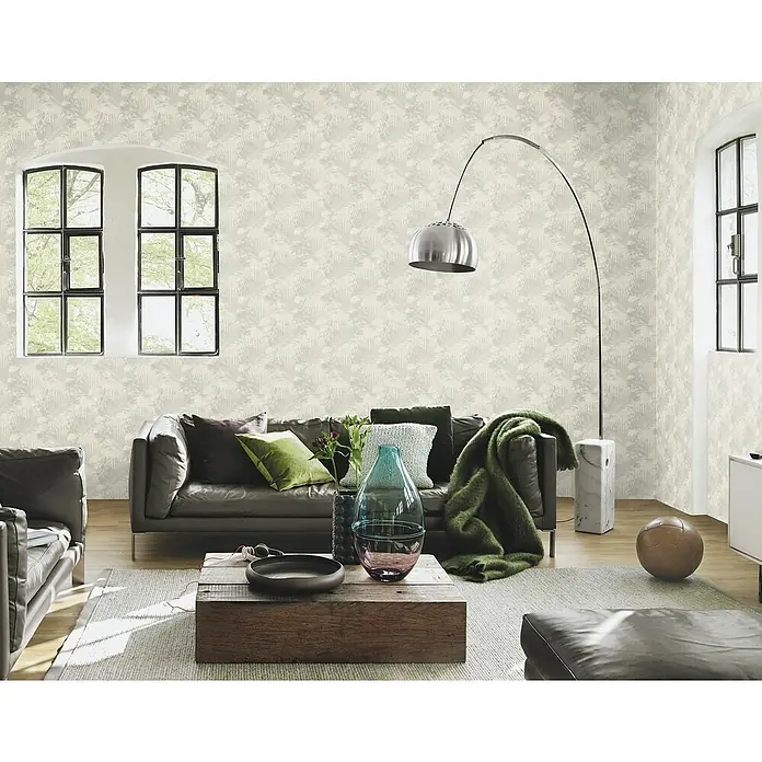 SCHÖNER WOHNEN-Kollektion Cosyliving Vliestapete TROPICAL Schattenblatt - Salbei, Floral, 10,05 x 0,53 m - Ein stilvolles Wohnzimmer mit einer Couch, einem Couchtisch und einer Stehlampe. Die Tapete hat ein dezentes Blättermuster.