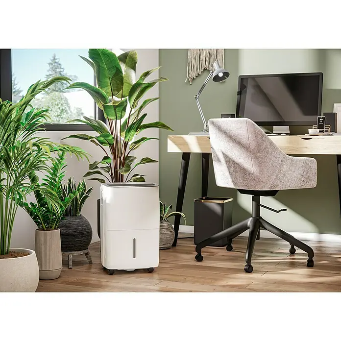 Voltomat Luftentfeuchter - Entfeuchtungsleistung: 60 l/Tag, Weiß/Grau, 900 W, Raumvolumen: 250 m³ - Büro mit einem weißen Luftentfeuchter neben mehreren Pflanzen, einem Schreibtisch und einem Bürostuhl für ein angenehmes Raumklima.