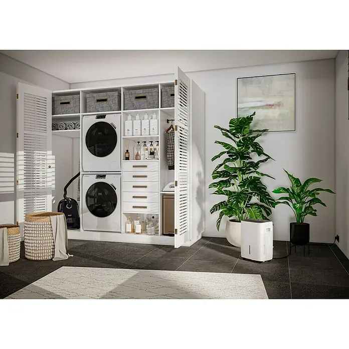 Voltomat Luftentfeuchter - Entfeuchtungsleistung: 40 l/Tag, Weiß/Grau, 680 W, Raumvolumen: 200 m³ - Ein moderner Waschraum mit weißer Waschmaschine und Trockner, eingebaut in einen Schrank, neben Zimmerpflanzen und einem Luftentfeuchter.