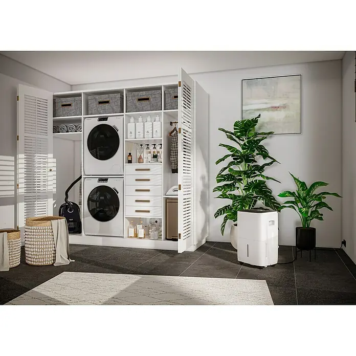 Voltomat Luftentfeuchter - Entfeuchtungsleistung: 60 l/Tag, Weiß/Grau, 900 W, Raumvolumen: 250 m³ - Waschküchen-Szene mit weißem Schranksystem, Waschmaschine, Trockner, Pflanzen und Luftentfeuchter für ein sauberes, frisches Zuhause.