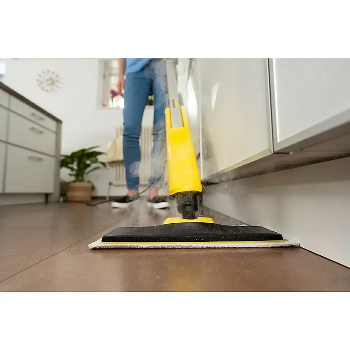 Kärcher Dampfreiniger SC 2 Upright EasyFix - 1.600 W, Aufheizzeit: 0,5 min, Behältervolumen: 0,4 l - Ein gelber Dampfreiniger wird verwendet, um einen braunen Boden neben einem weißen Schrank zu reinigen, wobei Dampf sichtbar ist.