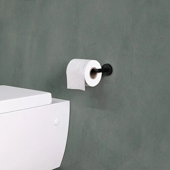 Cosmic Start Portarrollos papel higiénico - Negro - Primer plano de un portarrollos de papel higiénico negro con un rollo de papel higiénico blanco en una pared texturizada de color verde grisáceo, junto a un inodoro blanco.