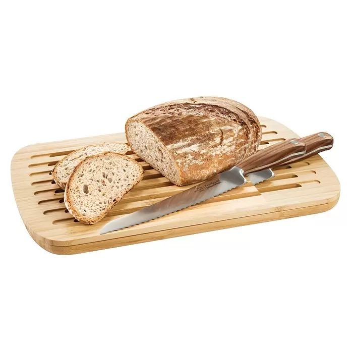 Tescoma Schneidebrett Online - 40 x 25 x 3 cm, Bambus - Rustikales Brot, auf einem Bambus-Schneidebrett mit Krümelfächern geschnitten, daneben ein gezacktes Brotmesser mit Holzgriff.