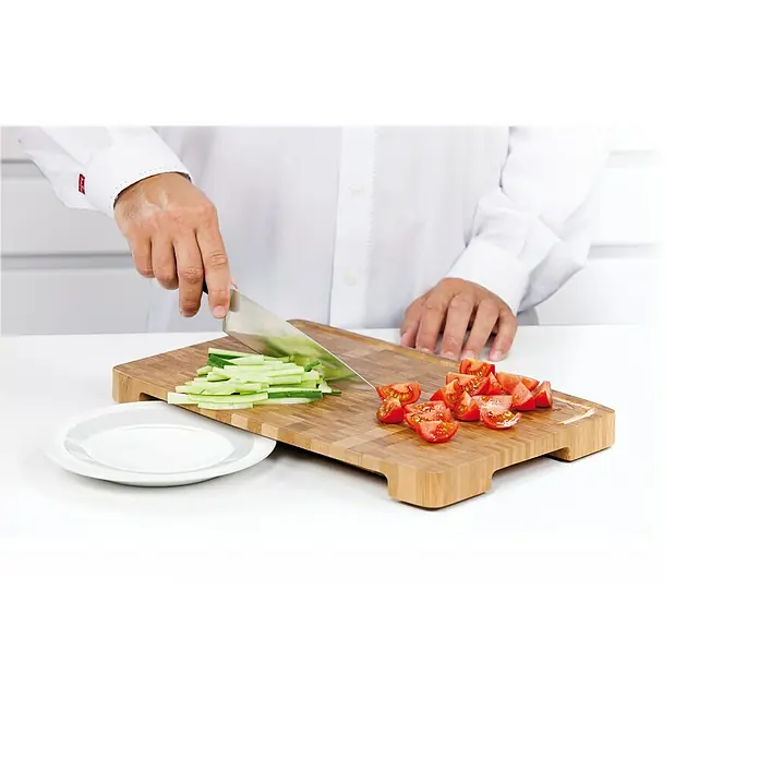 Tescoma Schneidebrett Azza - 50 x 33 x 4 cm, Bambus - Aufnahme einer Person beim Schneiden von Gurken und Tomaten auf einem Bambus-Schneidebrett mit einem Messer.