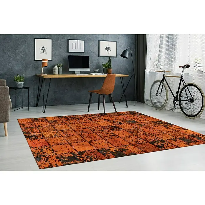 Kayoom Lederteppich Viola - Orange, 230 x 160 cm, 100 % Echtleder - Ein rechteckiger Teppich in Rostfarben mit dunklen Farbtupfern liegt in einem modern eingerichteten Raum.