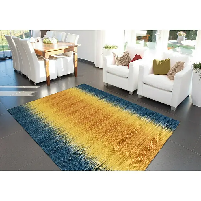 Kayoom Wollteppich Sunset - Gelb/Blau, 180 x 120 cm, 80 % Neuseeland-Wolle, 20 % Baumwolle - Ein moderner Teppich in Blau und Gelb liegt in einem hellen Wohnzimmer, das einladend und stilvoll wirkt.