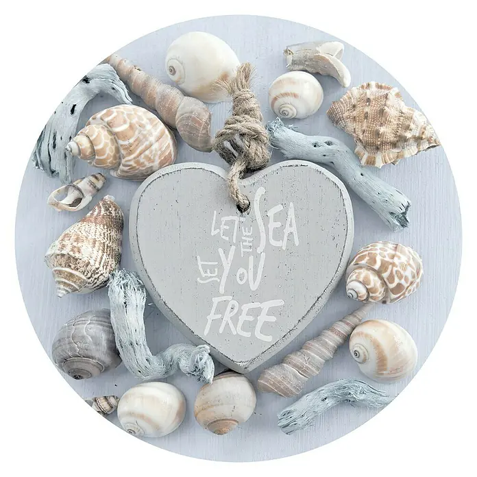 ProArt Glasbild - Maritim II, Durchmesser: 20 cm - Eine Nahaufnahme eines dekorativen hölzernen Herzanhängers mit der Aufschrift "Let the sea set you free", umgeben von verschiedenen Muscheln und Treibholz.