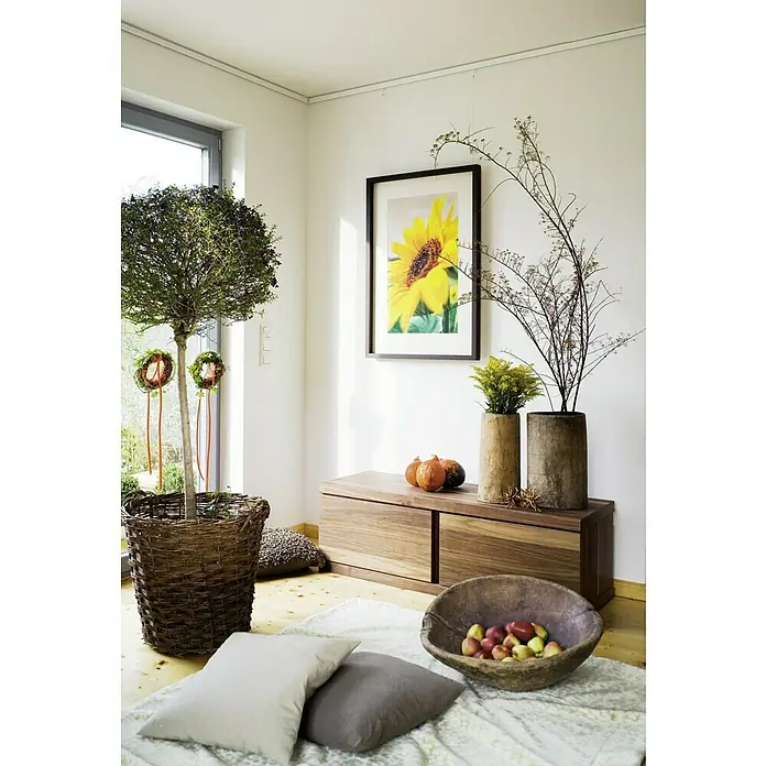Nielsen Galerieschiene Profi - Länge: 1,5 m, Weiß - Ein gemütliches Interieur mit einem üppigen Baum im Korb, Kürbissen und herbstlicher Deko auf einer Holzkommode unter einem Sonnenblumenbild.