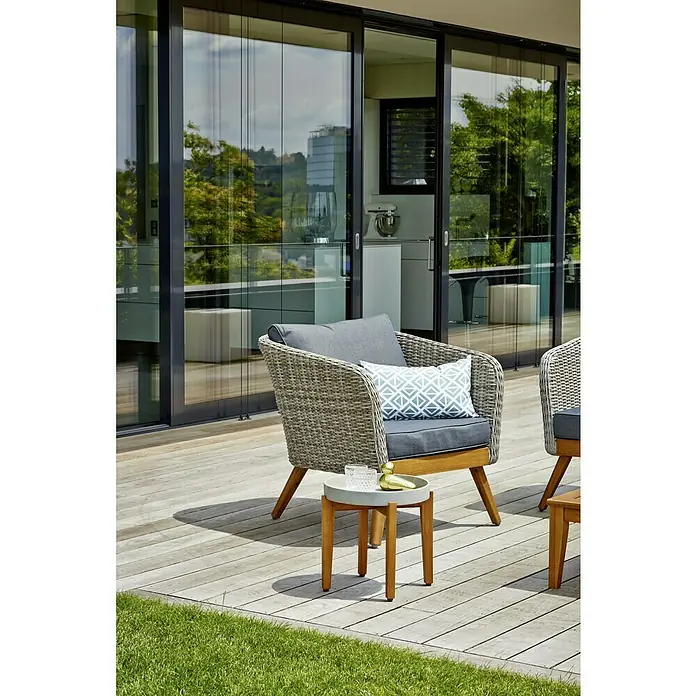 Sunfun Garten-Beistelltisch rund - Ø x H: 35 x 35 cm - Aufnahme eines Outdoor-Sessels mit grauem Kissen und Beistelltisch mit Deko auf einer Terrasse mit Schiebetüren im Hintergrund.