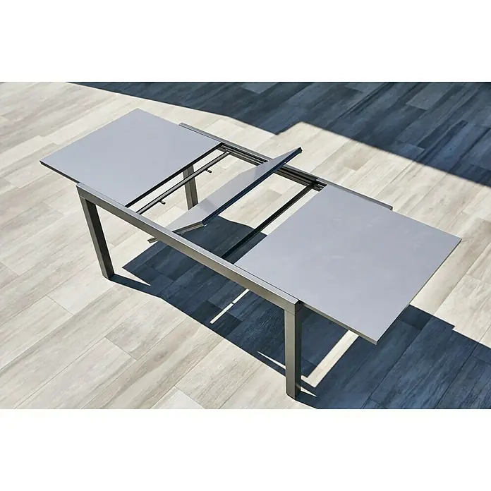Gartenmöbel-Set Maja/Carina - 7 -tlg., Glas/Aluminium/Akazie, Anthrazit/Naturbraun, Tischplatte ausziehbar - Ausgezogener grauer Gartentisch auf einer Terrasse. Das elegante Design wertet jeden Außenbereich auf und bietet ausreichend Platz.