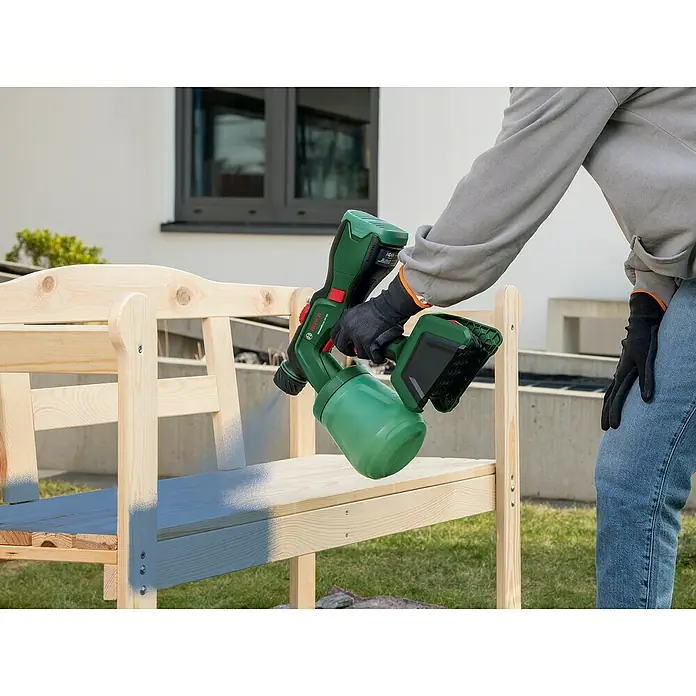Bosch Power for All 18V Akku-Farbsprühsystem Universal Spray 18V-300 - 18 V, Ohne Akku, Max. Fördermenge: 0,3 l/min - Eine Person sprüht mit einer Bosch Farbspritzpistole eine Holzbank, um sie zu lackieren.