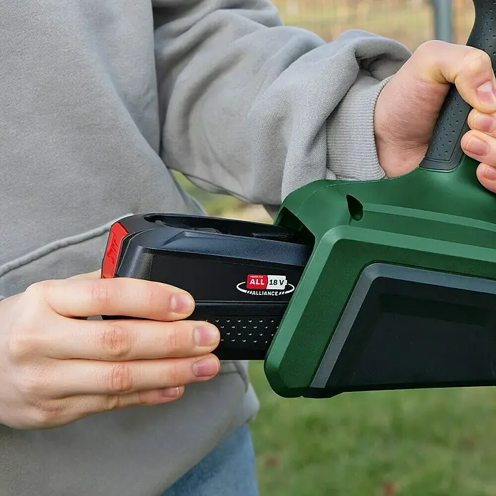 Bosch Power for All 18V Akku-Farbsprühsystem Universal Spray 18V-300 - 18 V, Ohne Akku, Max. Fördermenge: 0,3 l/min - Einsetzen des 18V Akkus in ein grünes Gartengerät. Der Akku ist schwarz mit rotem Akzent.