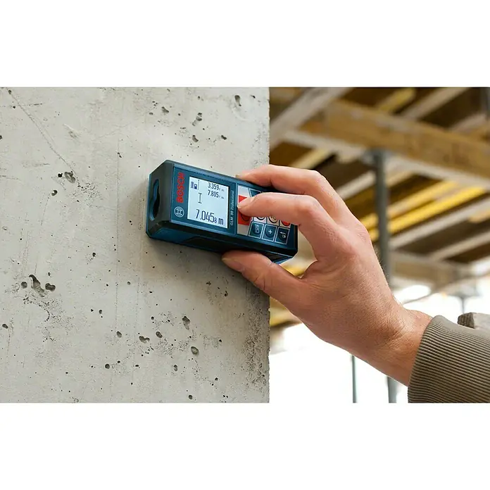 Bosch Professional Laserentfernungsmesser GLM 80 + Stativ BT150 - Messbereich: 0,05 - 80 m, Mit Stativ - Der Bosch GLM 80 Professional Laser-Entfernungsmesser wird von einer Hand bedient, um präzise Messungen an einer Betonwand durchzuführen.