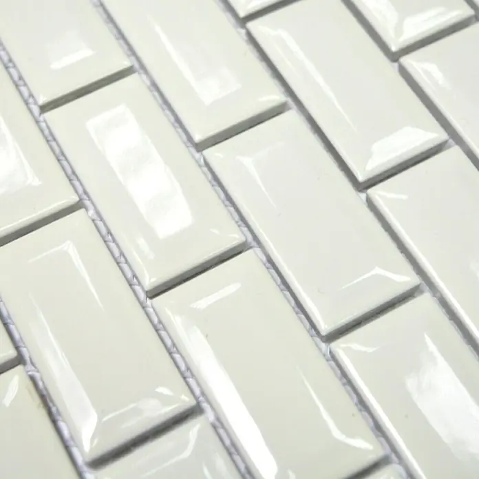 Mosaikfliese Brick Bond Diamond CBI 110 - 30 x 30 cm, Elfenbein, Glänzend - Nahaufnahme eines Musters aus weißen, rechteckigen Keramikfliesen, die im Fischgrätenmuster angeordnet sind und eine glänzende Oberfläche aufweisen.