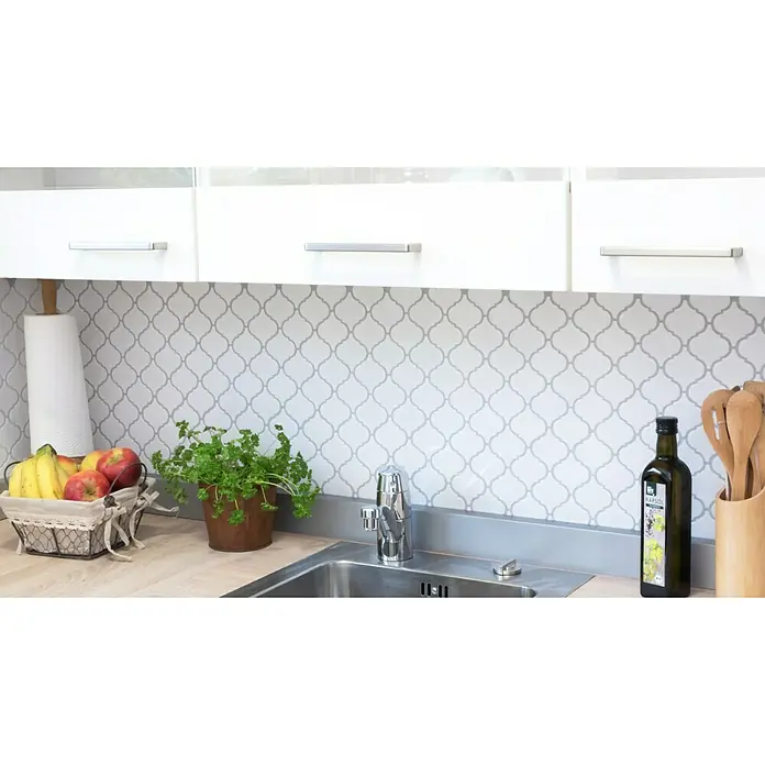 Mosaikfliese Florentiner Uni CLP 1WG - 29,3 x 24,5 cm, Weiß, Glänzend - Küchenstillleben mit Obstkorb, Kräutertopf, Olivenöl und Holzbesteck vor einem Fliesenspiegel.