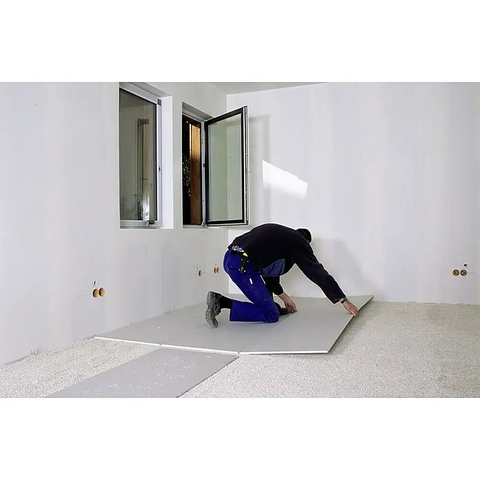 Knauf Gipskartonplatte GKB - 2.600 x 600 x 9,5 mm - Mann verlegt Trockenestrich-Elemente auf einem vorbereiteten Untergrund in einem hellen Raum mit Fenstern für eine ebene Bodenfläche.