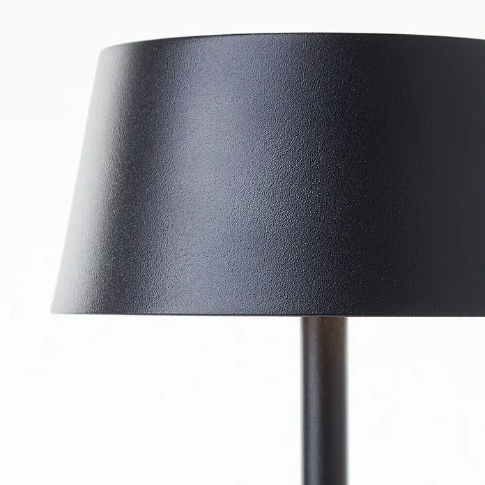 Brilliant Akku-Tischleuchte Picco - 4 W, Schwarz, Warmweiß - Nahaufnahme einer schwarzen Lampe mit konischem Lampenschirm, die ein modernes und stilvolles Design zeigt.
