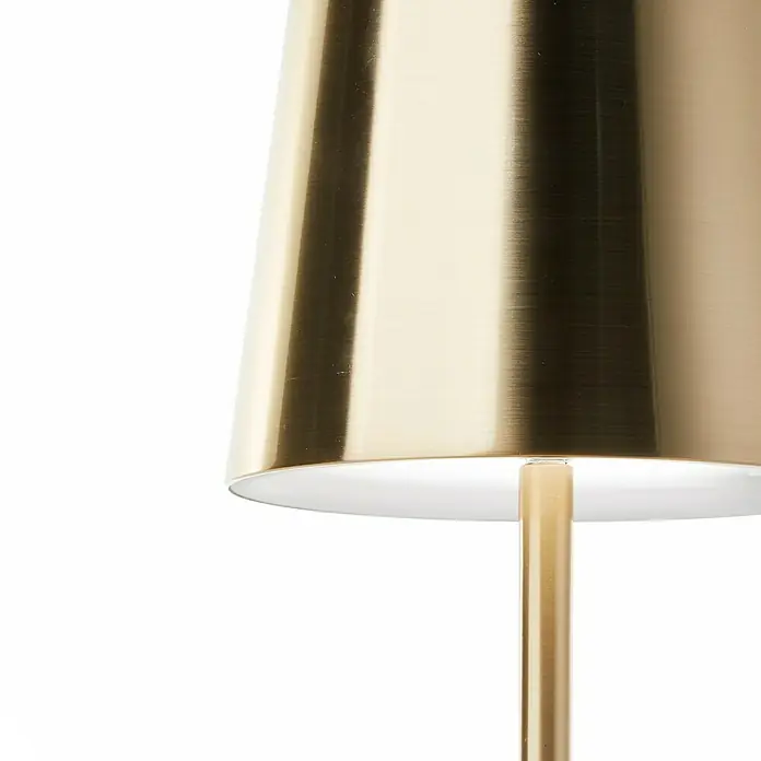 Brilliant Akku-Tischleuchte Xaana - 2 W, Gold, Mehrfarbig - Detailaufnahme einer eleganten, goldenen Lampe mit einem schlichten, konischen Lampenschirm und einem schlanken, goldenen Lampenfuß.