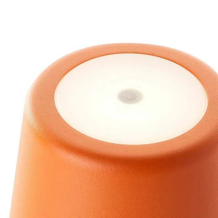 Brilliant Akku-Tischleuchte Kaami - 2 W, Orange, Warmweiß - Nahaufnahme einer orangefarbenen Lampe mit einem runden, leuchtenden Knopf in der Mitte, der eine sanfte Beleuchtung abgibt.