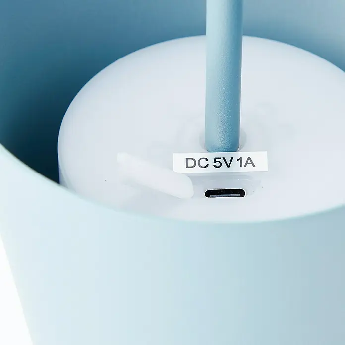 Brilliant Akku-Tischleuchte Kaami - 2 W, Mint, Warmweiß - Nahaufnahme des USB-C-Ladeanschlusses und des „DC 5V 1A“-Eingangsaufklebers eines hellblauen Elektronikgeräts.