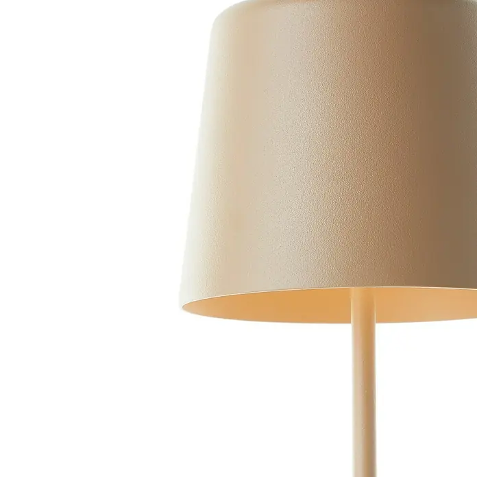 Brilliant Akku-Tischleuchte Kaami - 2 W, Cappuccino, Warmweiß - Nahaufnahme einer beigen Tischlampe mit kegelförmigem Schirm, die ein warmes Licht ausstrahlt.