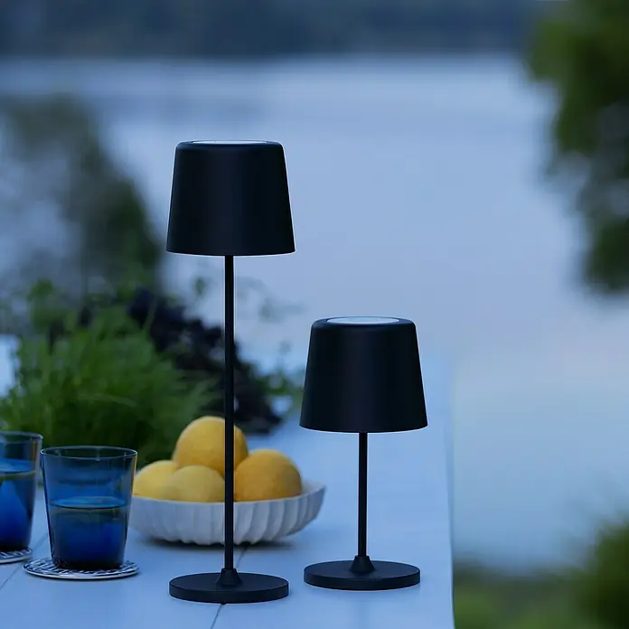 Brilliant Akku-Tischleuchte Kaami - 2 W, Schwarz, Warmweiß - Zwei elegante, schwarze Tischleuchten auf einem Tisch mit Gläsern und Zitronen im Freien.