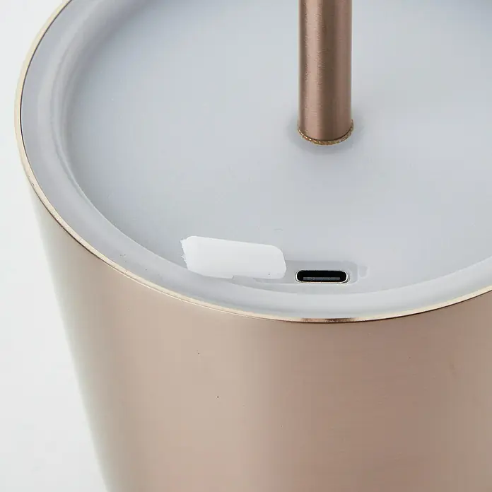 Brilliant Akku-Tischleuchte Xaana - 2 W, Kupfer, Mehrfarbig - Nahaufnahme eines Luftbefeuchters in Roségold mit einem USB-C-Anschluss und einem weißen Gummistopfen, der das Gerät verschließt.