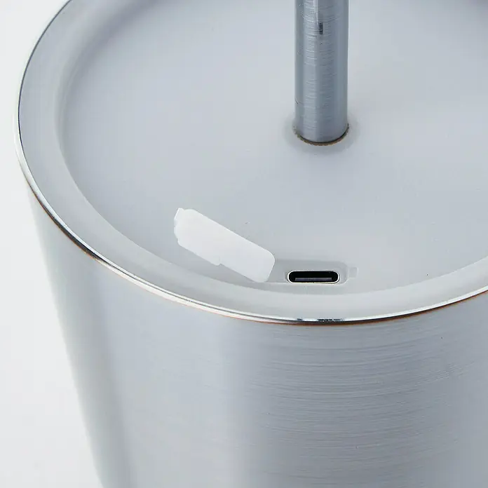 Brilliant Akku-Tischleuchte Xaana - 2 W, Silber, Mehrfarbig - Nahaufnahme einer grauen Lampe mit USB-Anschluss und einem kleinen weißen Stecker, der daneben liegt. Das elegante Design betont die moderne Ästhetik.