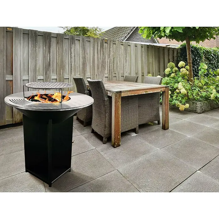 Purline Barbacoa de carbón EFP56B - Diámetro de la superficie de la parrilla: 98 cm, Negro - Un brasero con parrilla en un patio con una mesa y sillas. El brasero es un atractivo en la zona exterior.