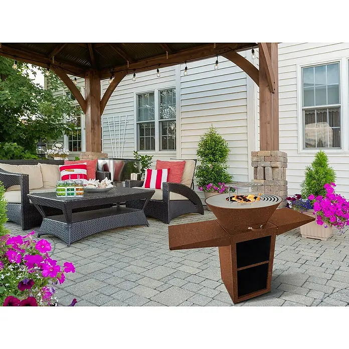 Purline Barbacoa de carbón EFP57CO - Diámetro de la superficie de la parrilla: 60 cm, Óxido - Elegante fogón con función de parrilla para horas agradables al aire libre, rodeado de muebles de jardín y plantas florecientes.