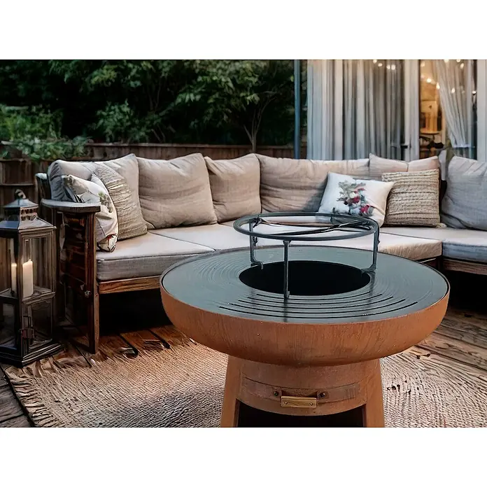 Purline Barbacoa de carbón EFP55CO - Diámetro de la superficie de la parrilla: 60 cm, Óxido - Ambiente atmosférico con un moderno brasero de exterior, rodeado de cómodos asientos y luces suaves.