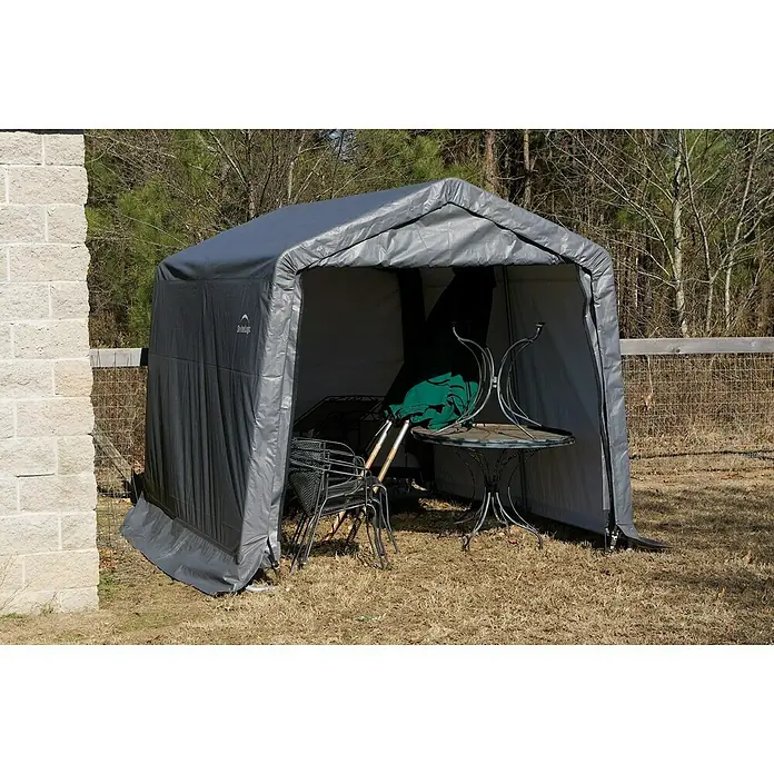 ShelterLogic Gerätehaus - Außenbreite inkl. Dachüberstand: 297 cm, Außentiefe inkl. Dachüberstand: 305 cm, Stahl, Grau - Eine graue Gerätehütte mit Gartentisch und Stühlen darin. Die Hütte bietet Schutz vor Witterungseinflüssen und hält die Möbel sauber.