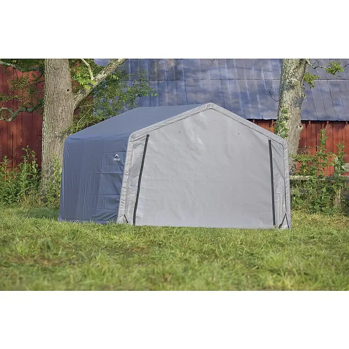 ShelterLogic Gerätehaus - Außenmaß inkl. Dachüberstand (B x T): 370 x 370 cm, Kunststoff, Grau - Eine graue Lagerzelthalle von ShelterLogic steht im Freien auf einer Rasenfläche mit Bäumen und einem roten Gebäude im Hintergrund.
