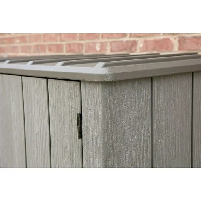 Lifetime Geräteschrank - Außenbreite inkl. Dachüberstand: 136 cm, Außentiefe inkl. Dachüberstand: 70 cm, Kunststoff, Dunkelgrau - Detailaufnahme eines grauen Gartenschranks aus Holz mit einer dunkelgrauen Oberseite, der vor einer Ziegelwand steht.