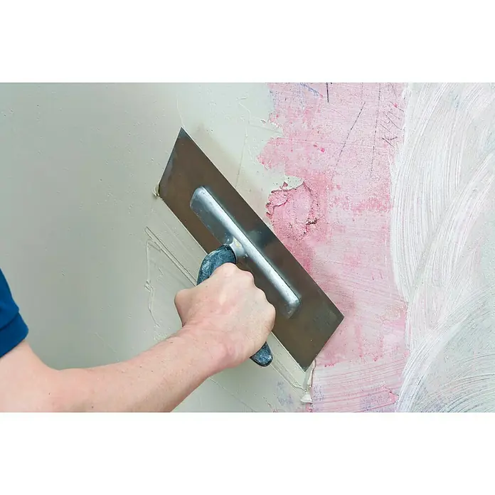 Knauf Rotband Haftputzgips - 30 kg - Nahaufnahme einer Person, die mit einer Glättkelle eine Wand verputzt, wobei die Textur und die Werkzeugführung im Fokus stehen.
