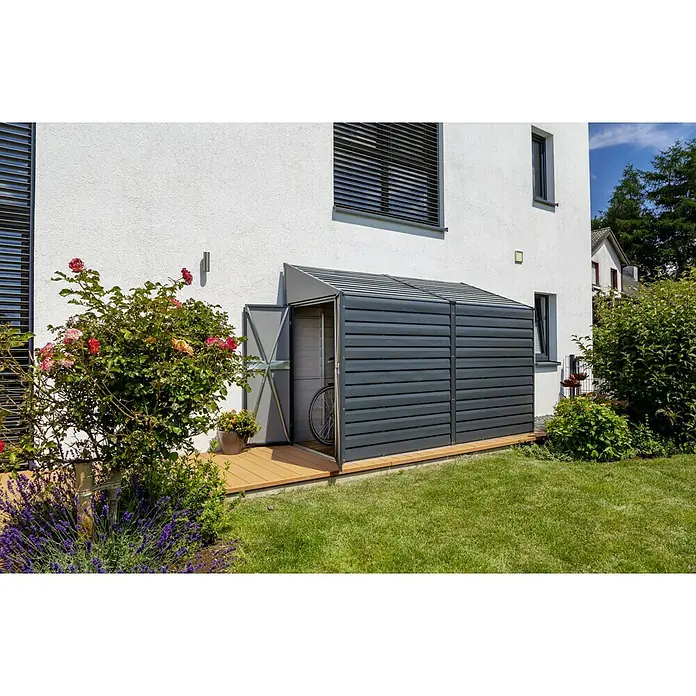 Spacemaker Gerätehaus 4x10 - Außenmaß inkl. Dachüberstand (B x T): 124,5 x 294,6 cm, Stahl, Grau - Eine graue Gerätebox aus Kunststoff steht an einer Hauswand, die Tür ist offen und ein Fahrrad steht darin.