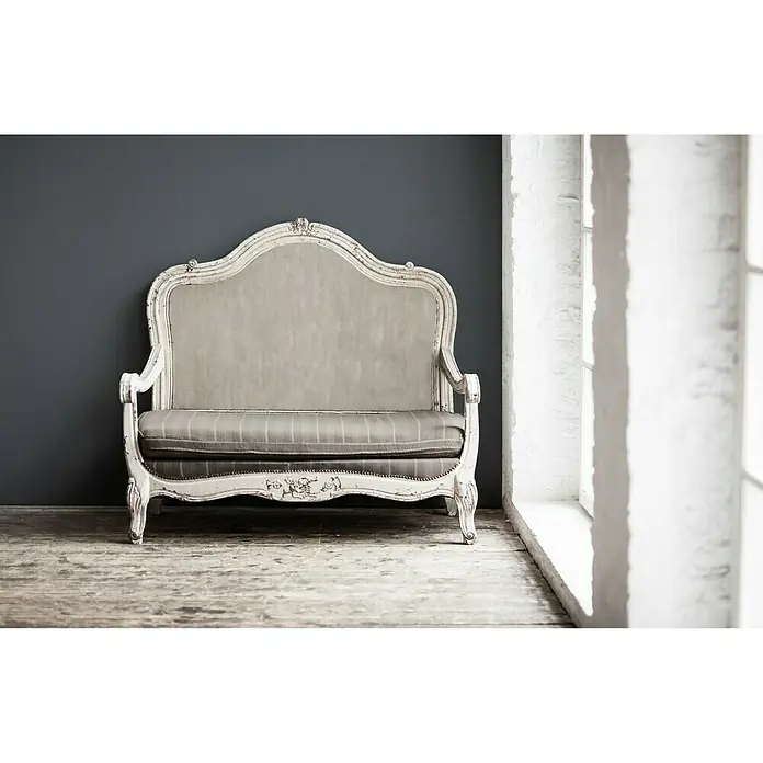 A.S. Création Vliestapete Elegance - Grau, Uni, 10,05 x 0,53 m - Antikes Sofa mit weißem Rahmen und grauem Bezug vor dunkler Wand und Fenster.