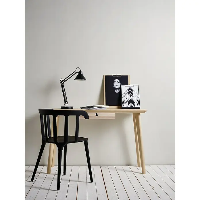 A.S. Création Vliestapete PutzoptikWeiß, Uni, 10,05 x 0,53 m - Schreibtisch-Setup mit einer eleganten schwarzen Lampe, einem schlanken Schreibtisch mit Schublade und einem stilvollen schwarzen Stuhl.