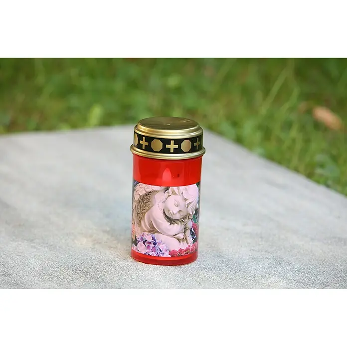 LED-Grablampe Tumba - Ø x H: 7 x 13 cm, Rot - Rote Grableuchte mit einem goldenen Deckel, verziert mit einem Engel-Motiv und Blumen auf einem Grabstein.
